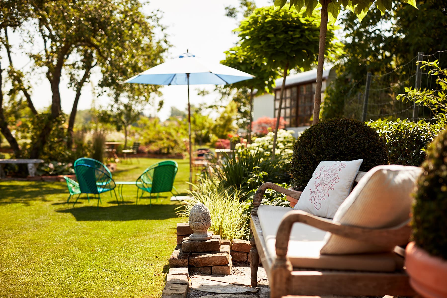 Lauschige Gartenlounge mit Sonnenschirm und blühenden Stauden