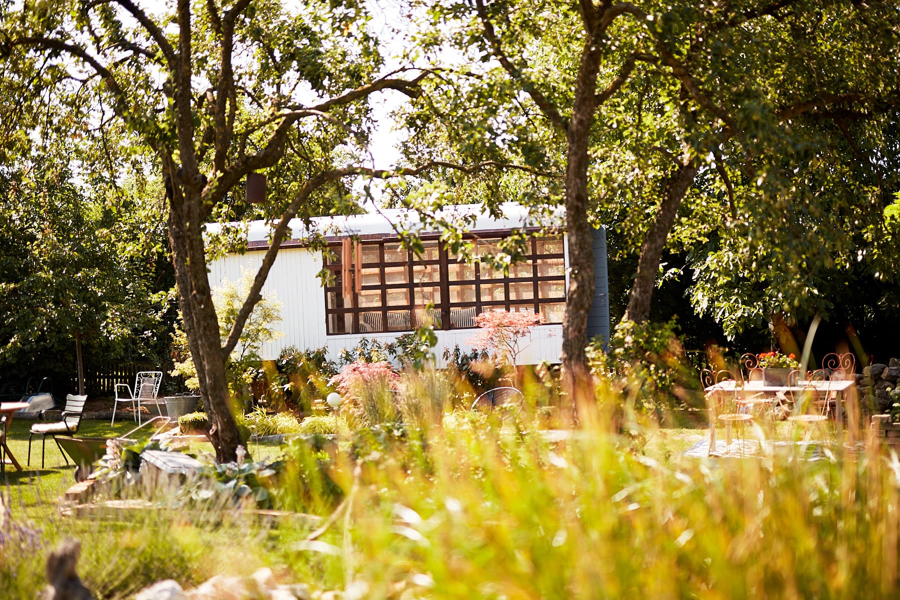 Pavillon im Schaugarten Trübensee mit Apfelbäumen und Wildblumen im Vordergrund